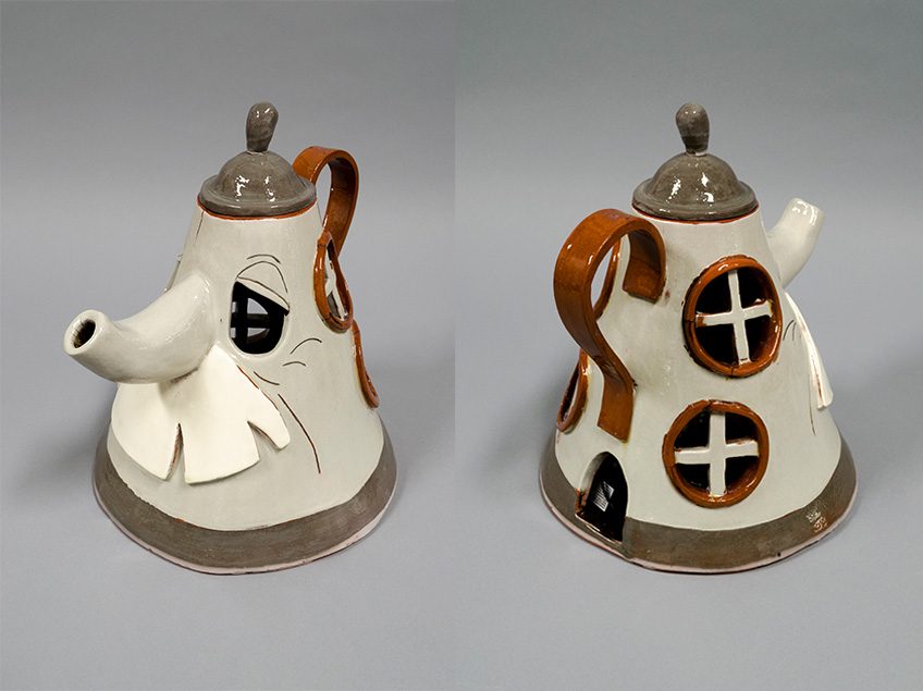 Wheel thrown cone-shaped vessel with a face. The nose is a spout and mustache is underneath. Windows are decorated around the vessel.