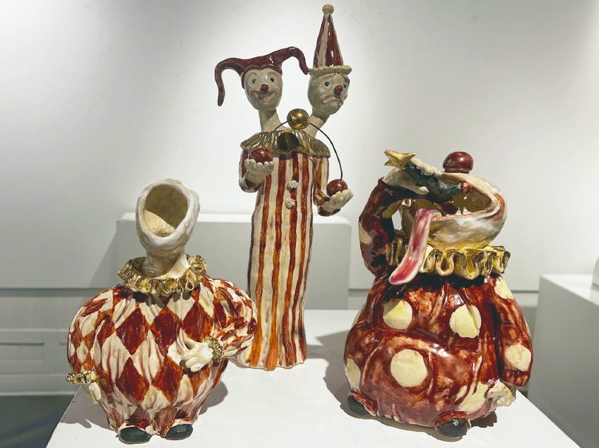 Three small clown sculptures each with different expressions, and decorated with red and gold accents.