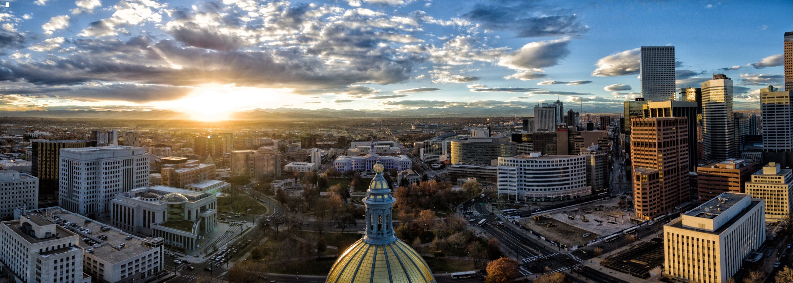 Beautiful drone photograph of a sunset over the golden cupola of the Colorado Capital building in the city of Denver