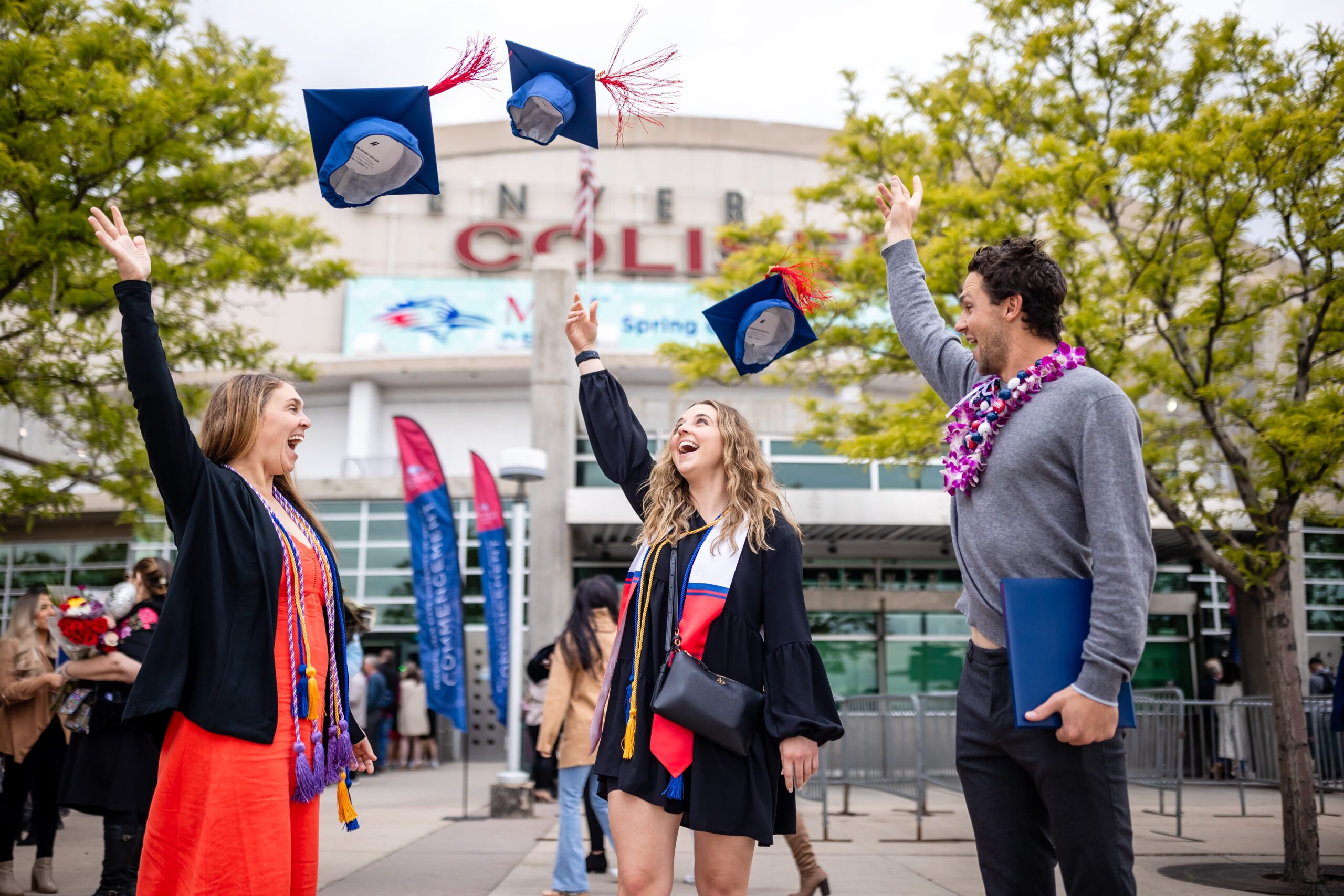 Three students throwing their caps into the air after the commencement ceremony.