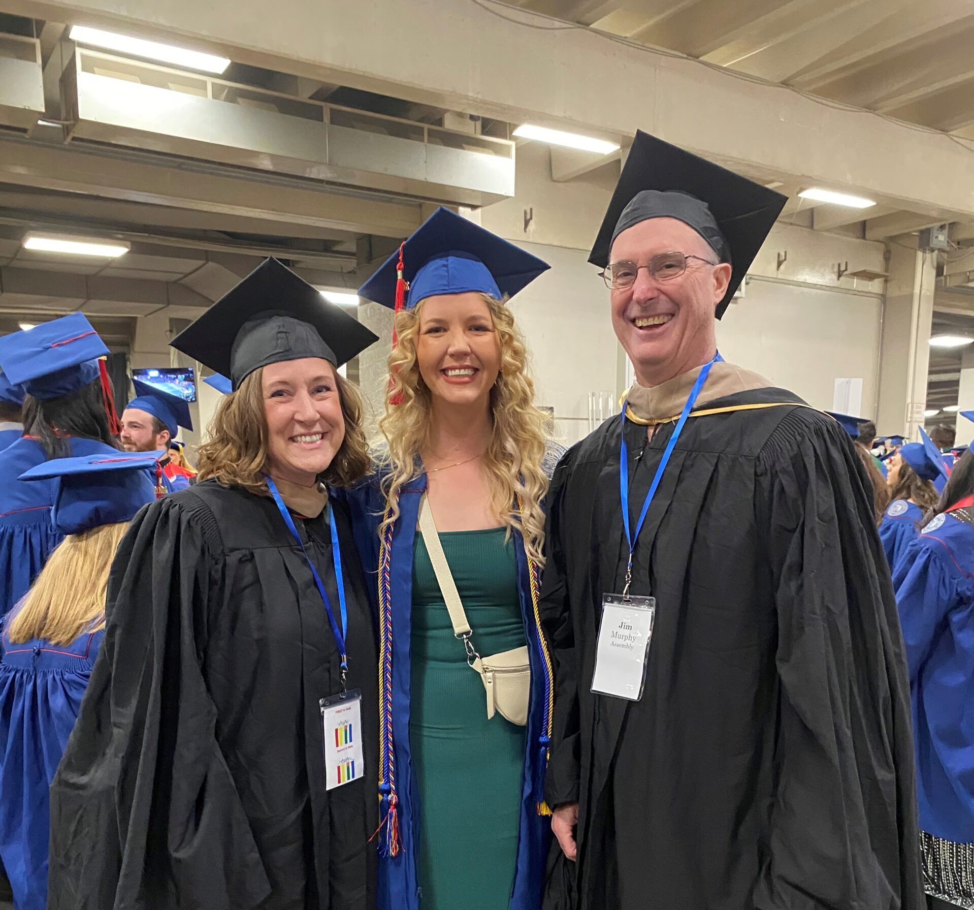 Spring 2024 Commencement photo - faculty (Jo & Jim) with graduating student (Molly - undergrad) in regalia as students line up