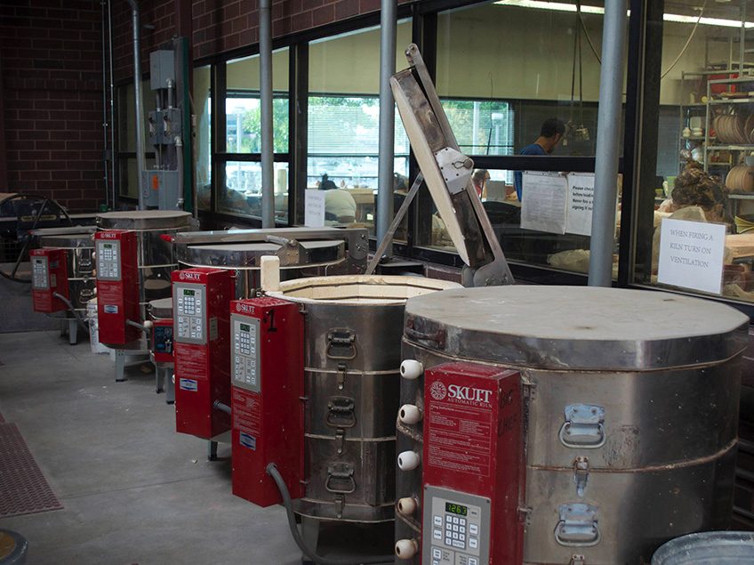 Photograph of 7 electric kilns in a row in the kiln yard at MSU Denver Department of Art ceramics studio.