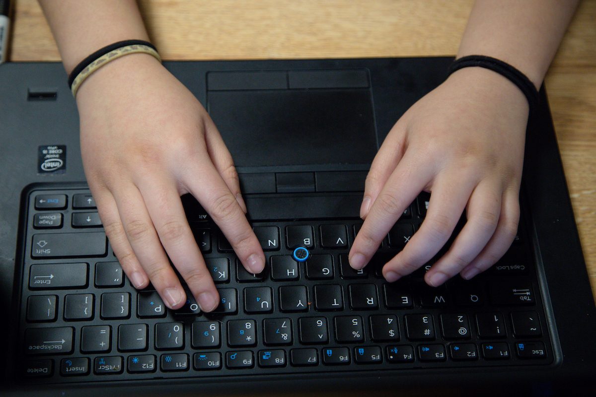 Student's hands seen from above typing on a keyboard