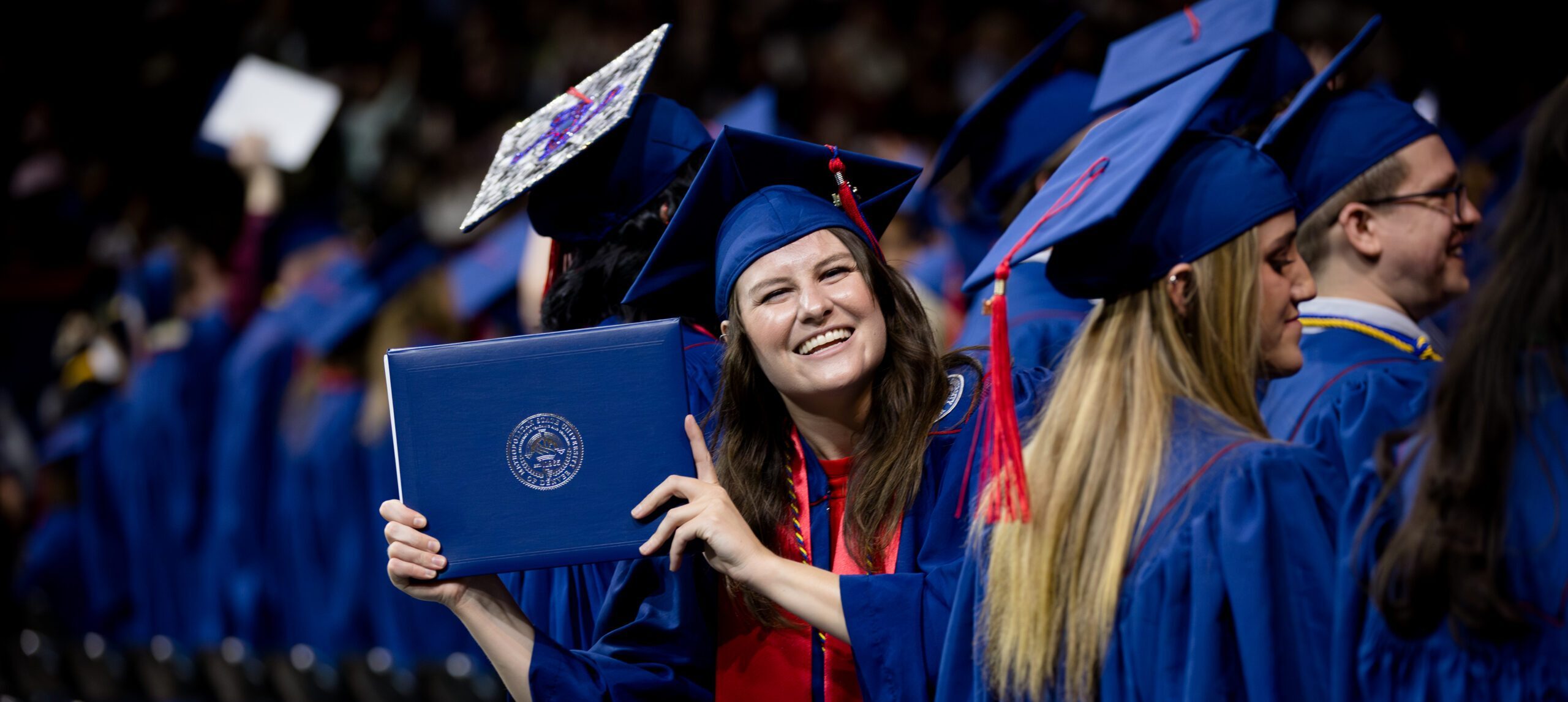 A graduate displays their diploma cover at Commencement