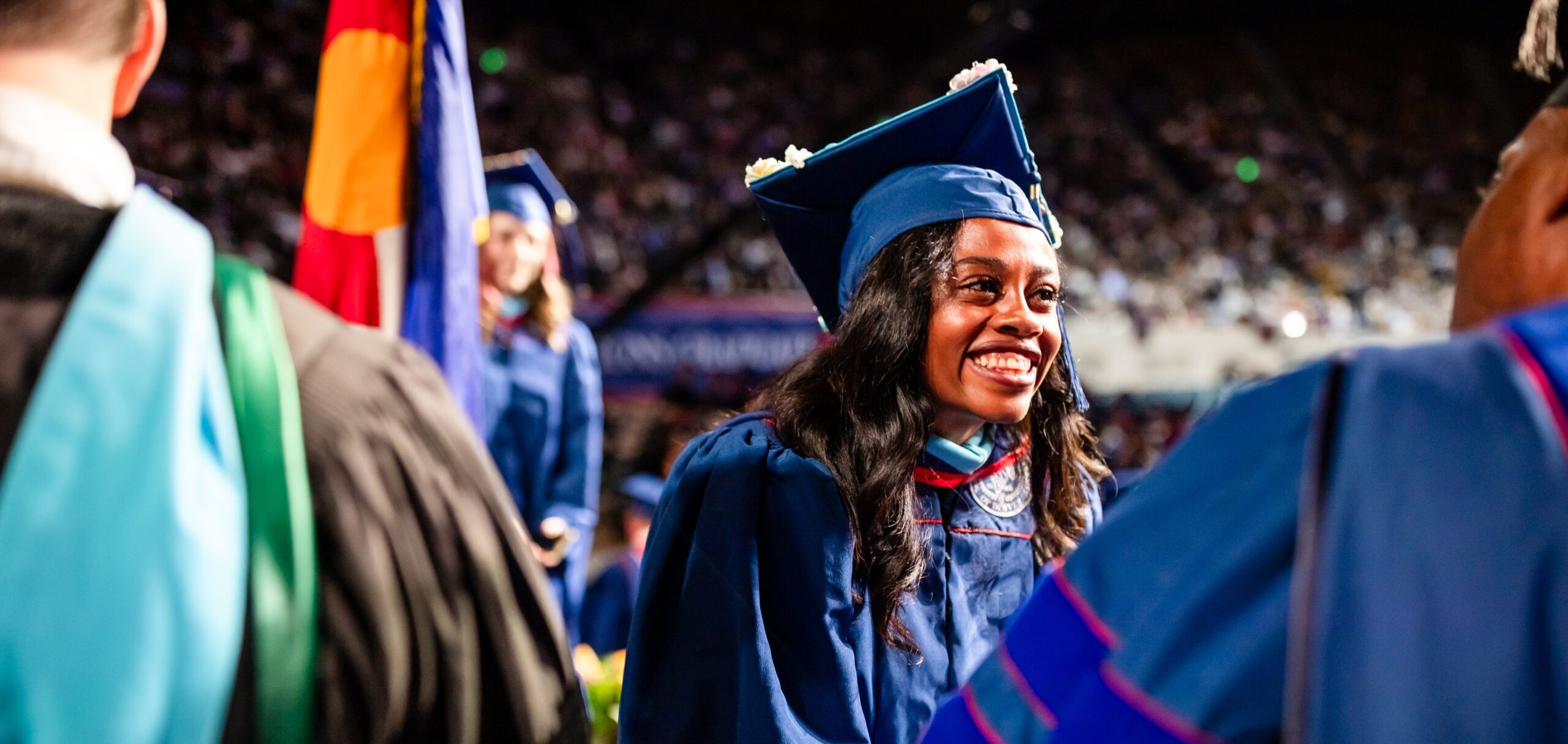 A graduate receives their diploma cover on stage at Commencement