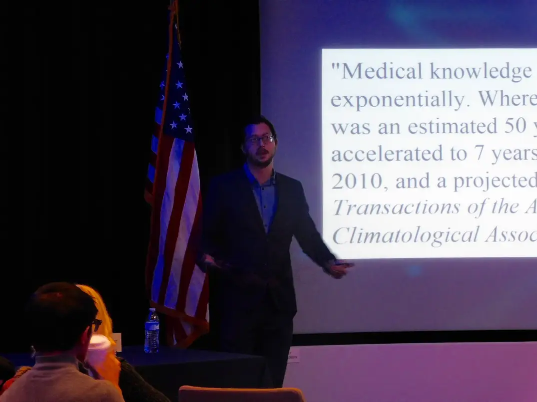Gabriel speaking in front of a powerpoint slide