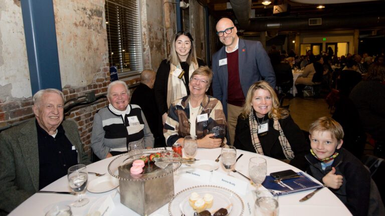 Jenny Price sitting with family and friends around a table at the MSU Denver Scholarship Dinner in the Tivoli Turnhalle