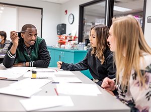 Students in a classroom discuss a group project.