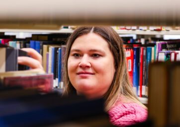 MSU Denver social work graduate student Christy Walker pulls a book off a shelf in the Auraria Library