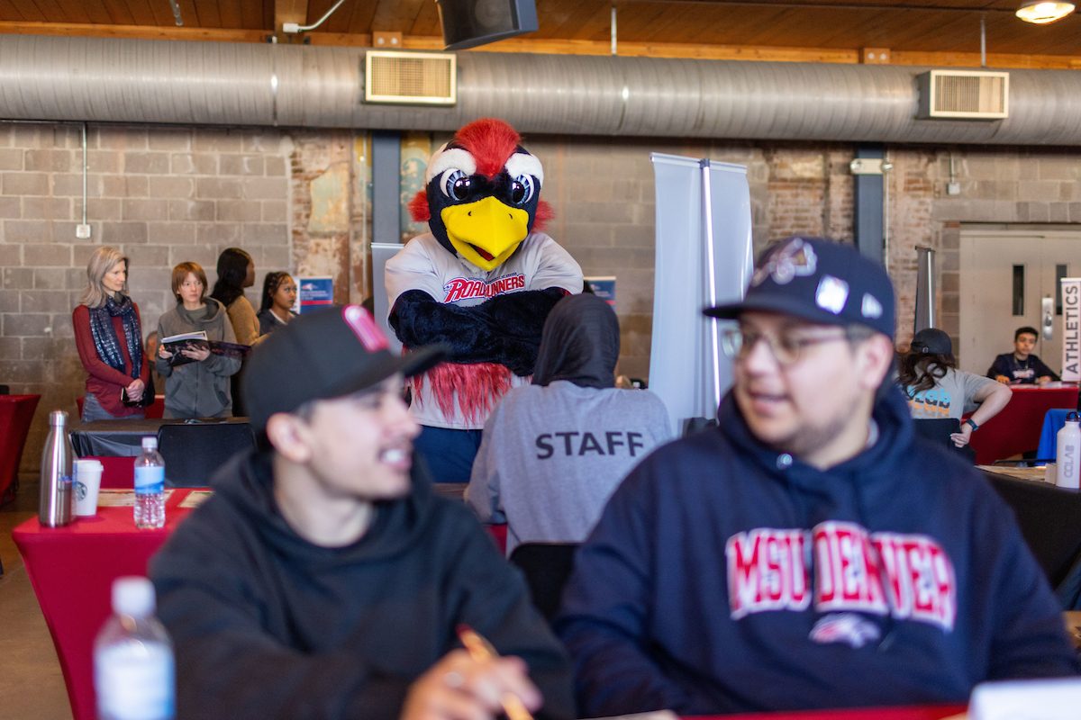 Two students in the foreground with Rowdy the Roadrunner posing in the background