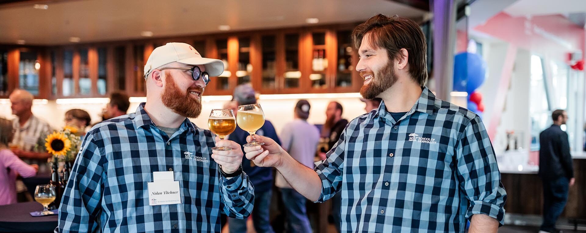 Two men holding up glasses of beer and cheersing at the MSU Denver mug club