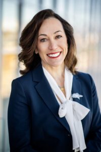 President Janine Davidson smiling, wearing a navy blazer with a white blouse