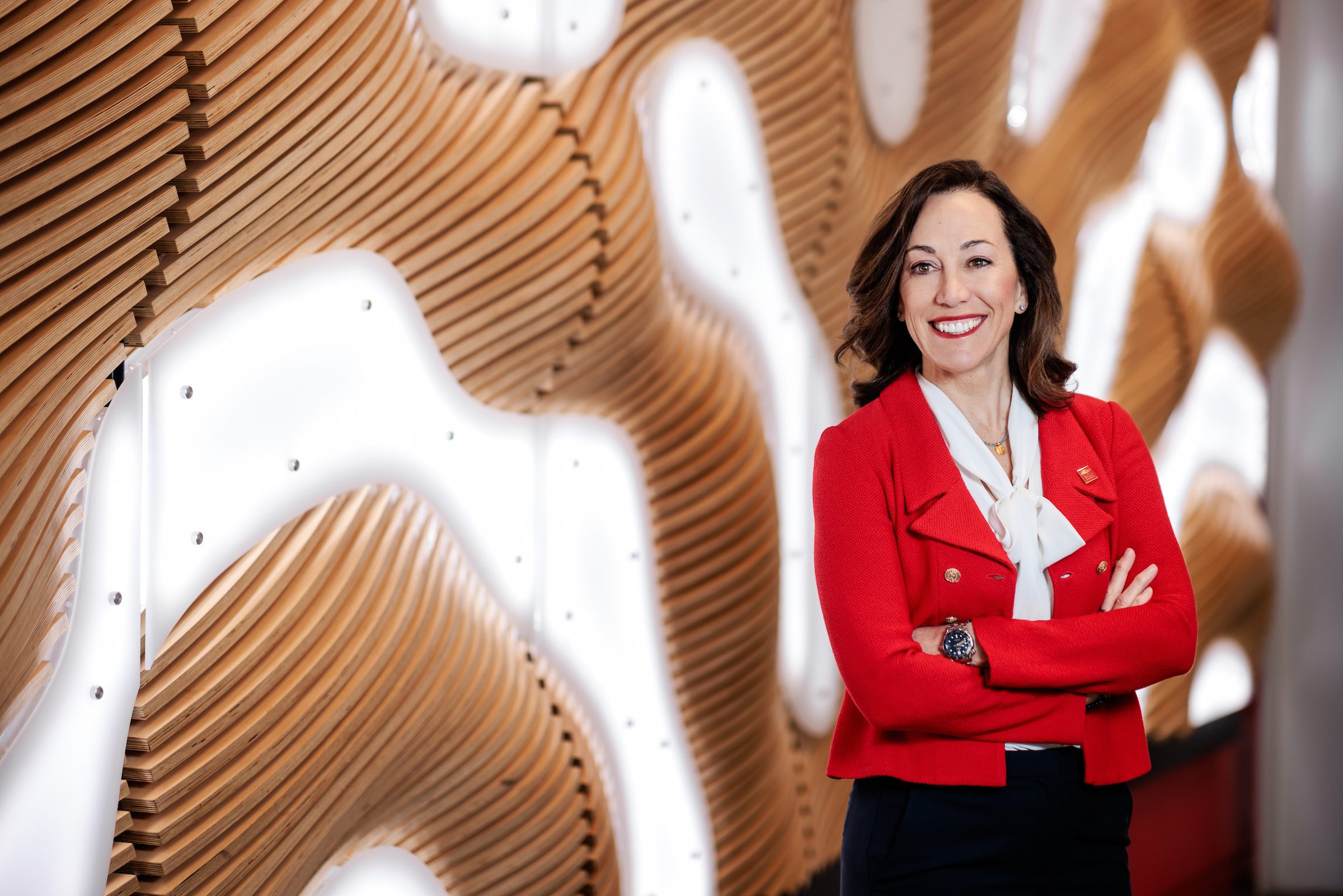 President Janine Davidson wearing a red blazer in front of an illuminated background.