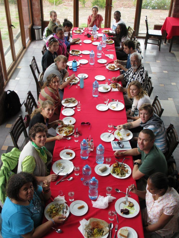 The MSU Denver Office of International Studies holding a dinner with a group of people at a long table in Ethiopia