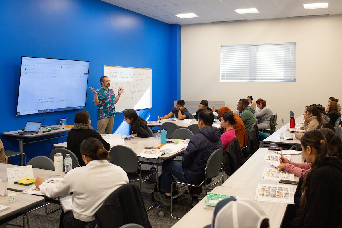 A teaching to a classroom of students sitting at tables