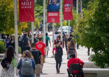 Students walking on campus near flagpoles with MSU Denver banners