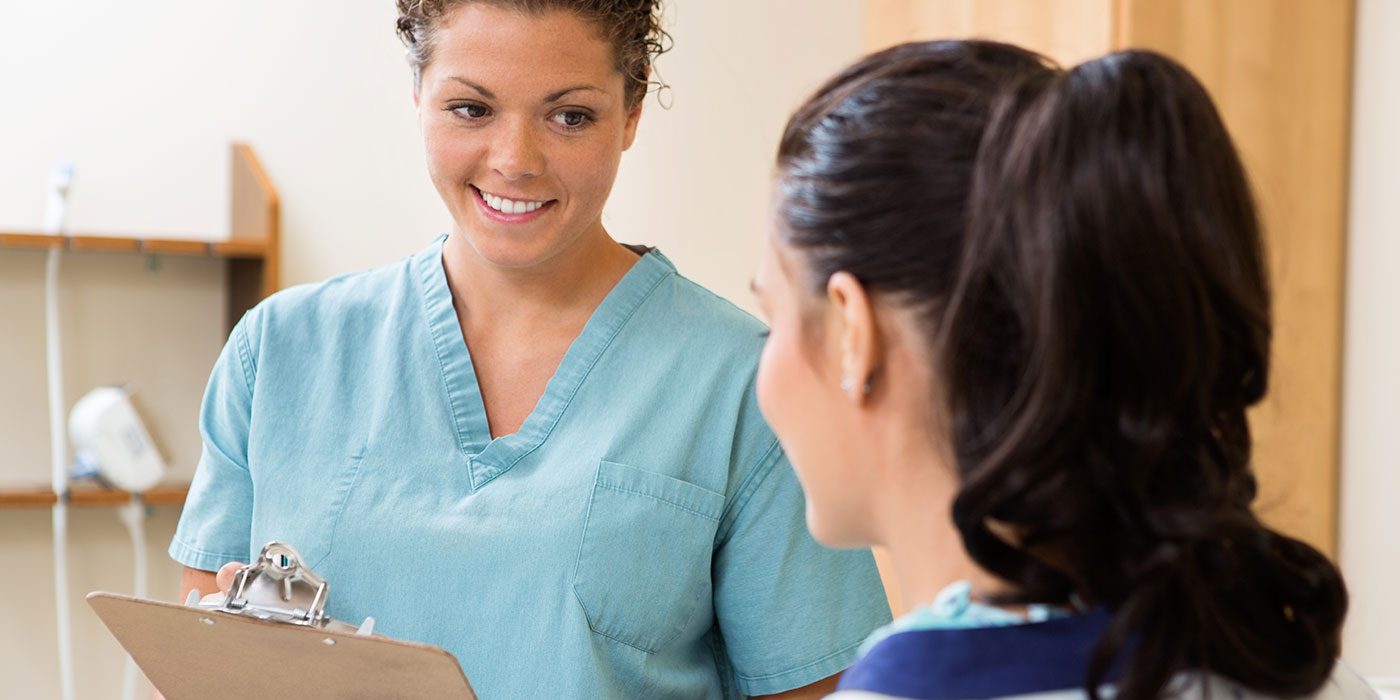 Medical assistant with clipboard talking to patient