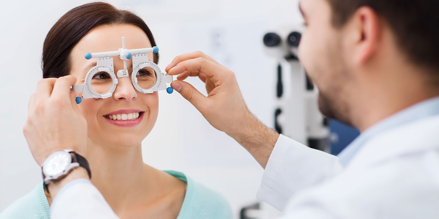 Male eye doctor testing eyes of female patient.