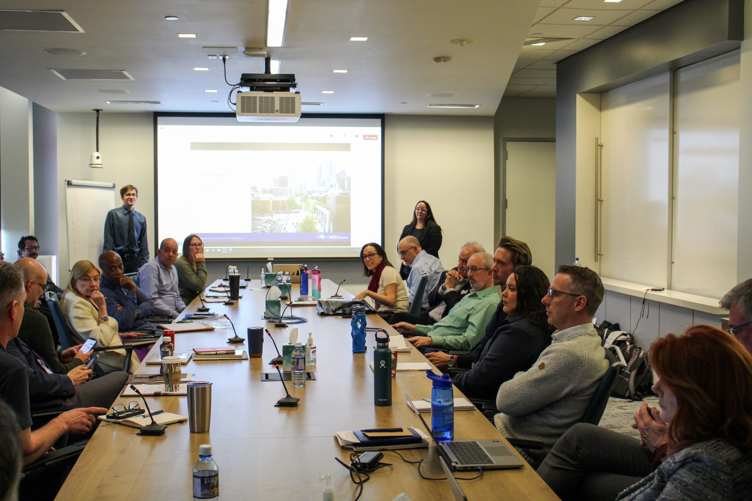 senior leaders at a boardroom-style table asking questions after student internal audit presentation