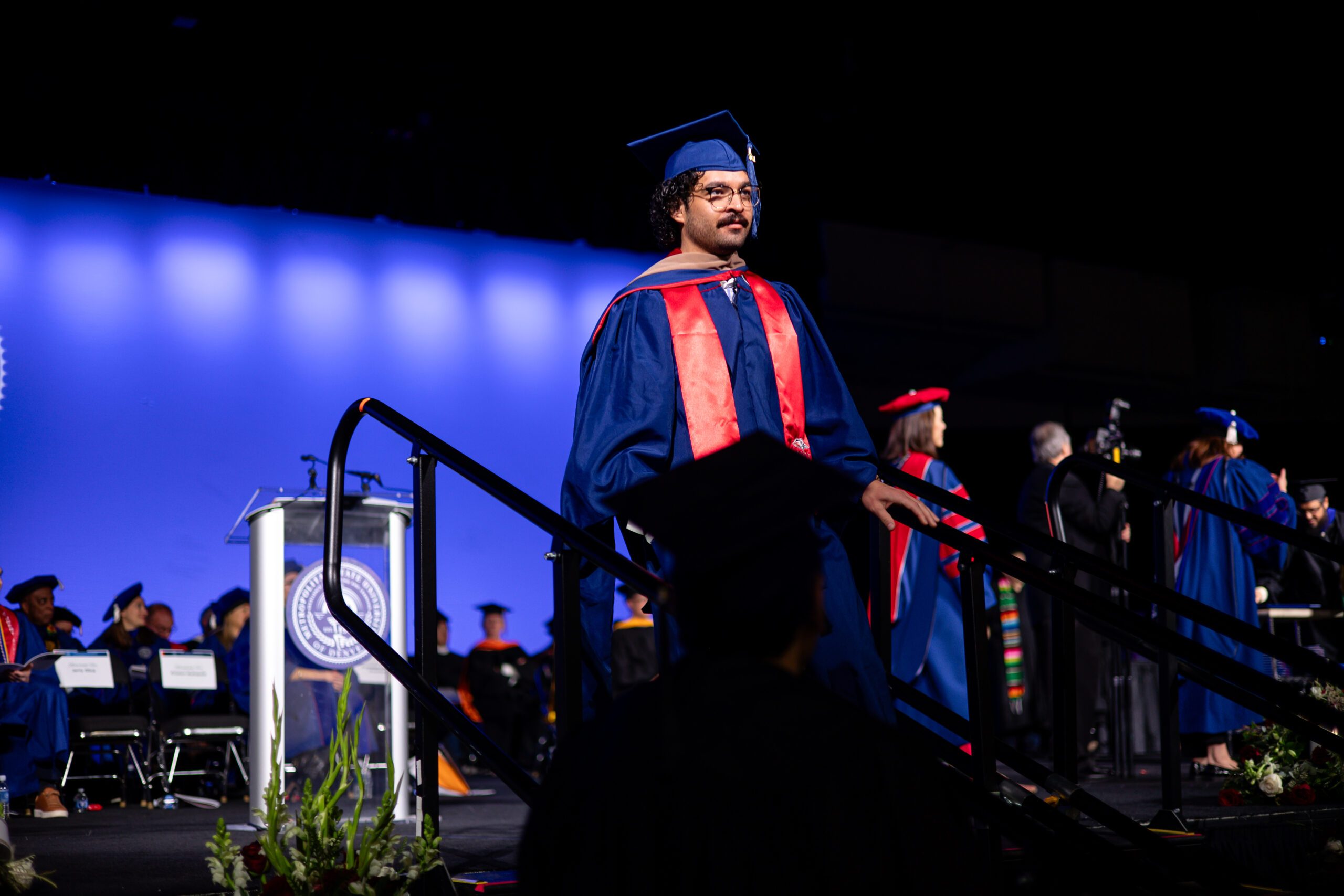 MPAcc graduate walking down stairs after crossing stage with diploma cover in hand