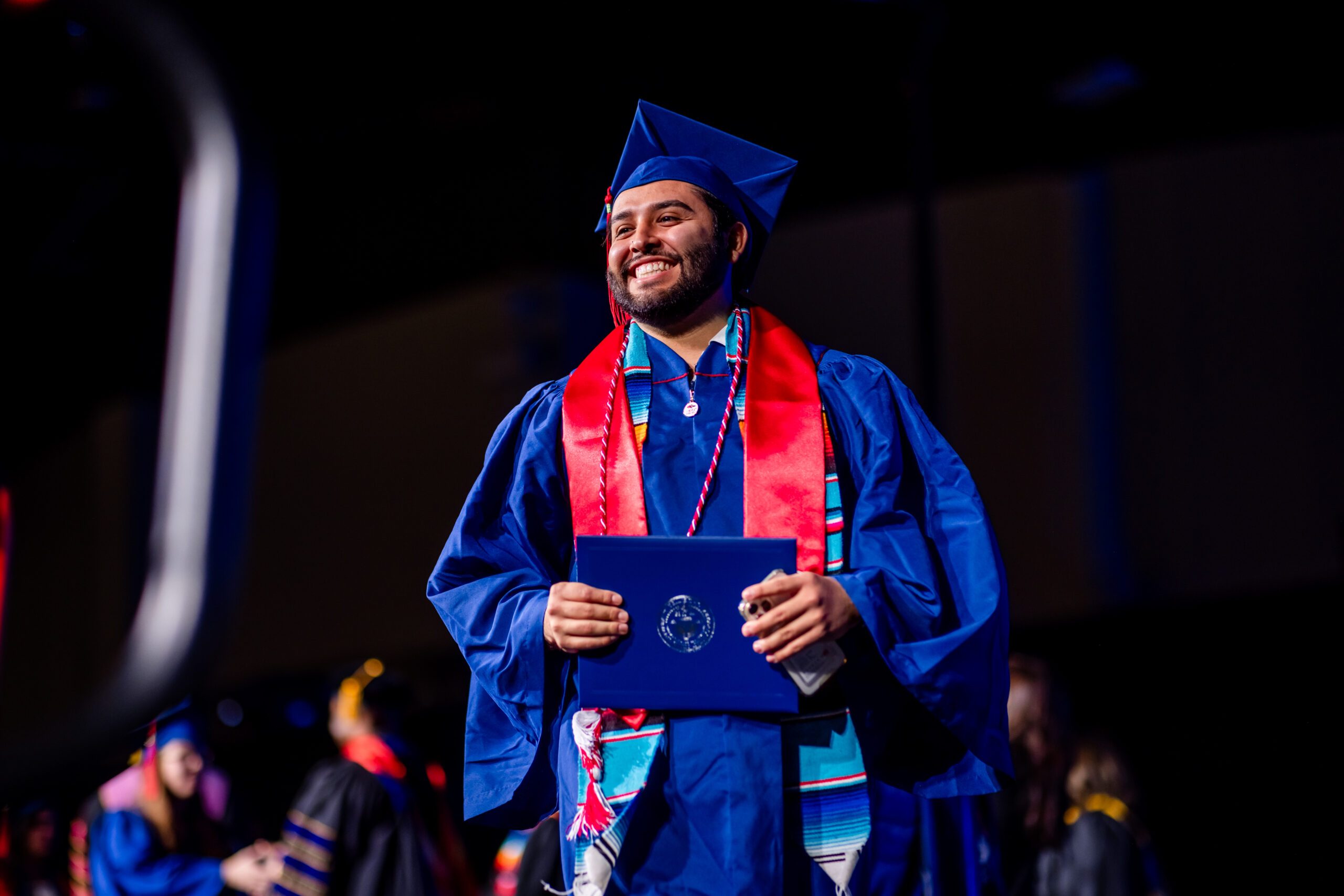 accounting graduate smiling and holding diploma cover walking off stage