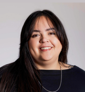 Woman, Shayla Bischoff, posing for a headshot. Black shirt, long black hair, smiling