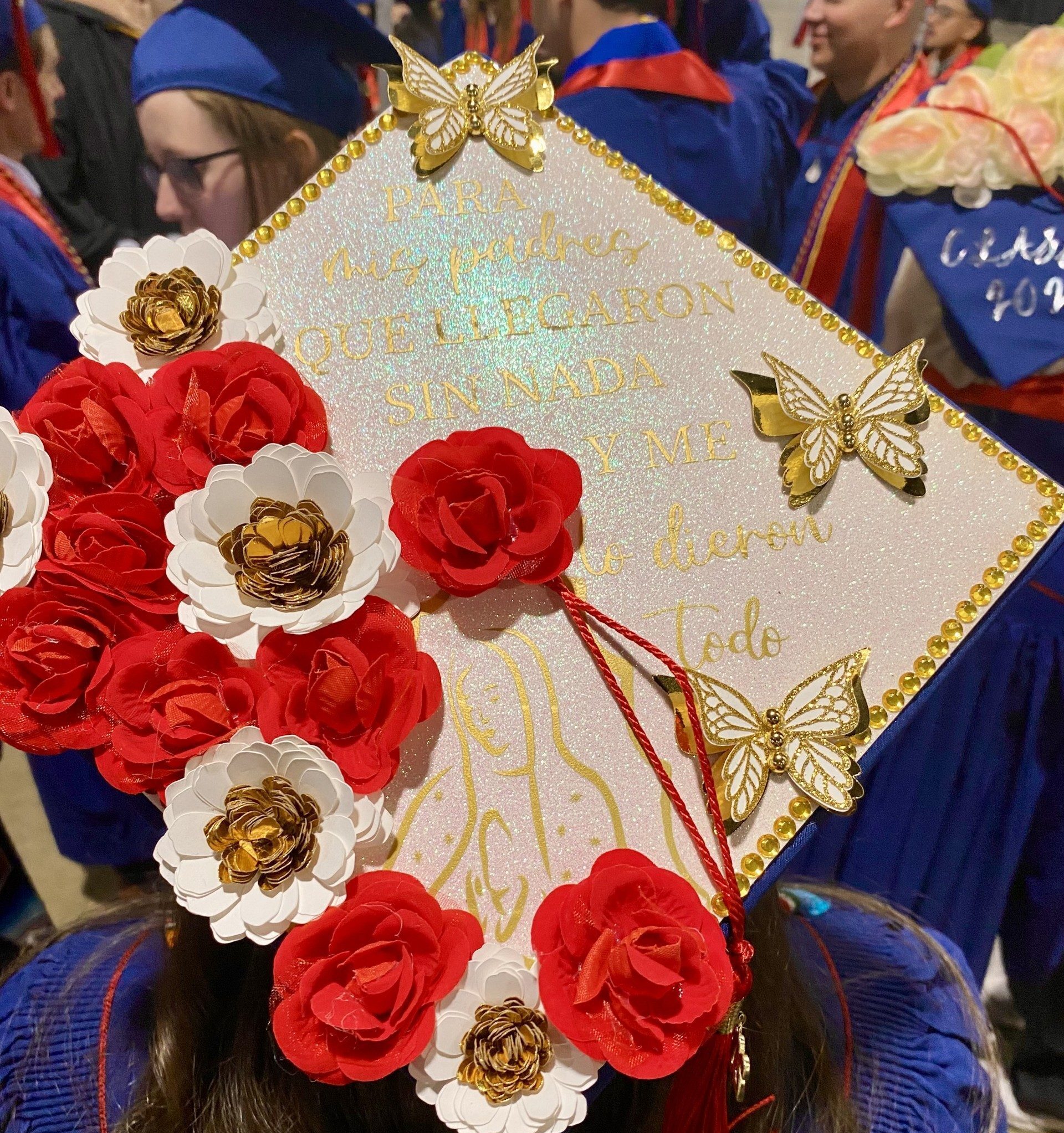 decorated grad cap with red and white flowers and gold butterflies at Fall '24 commencement