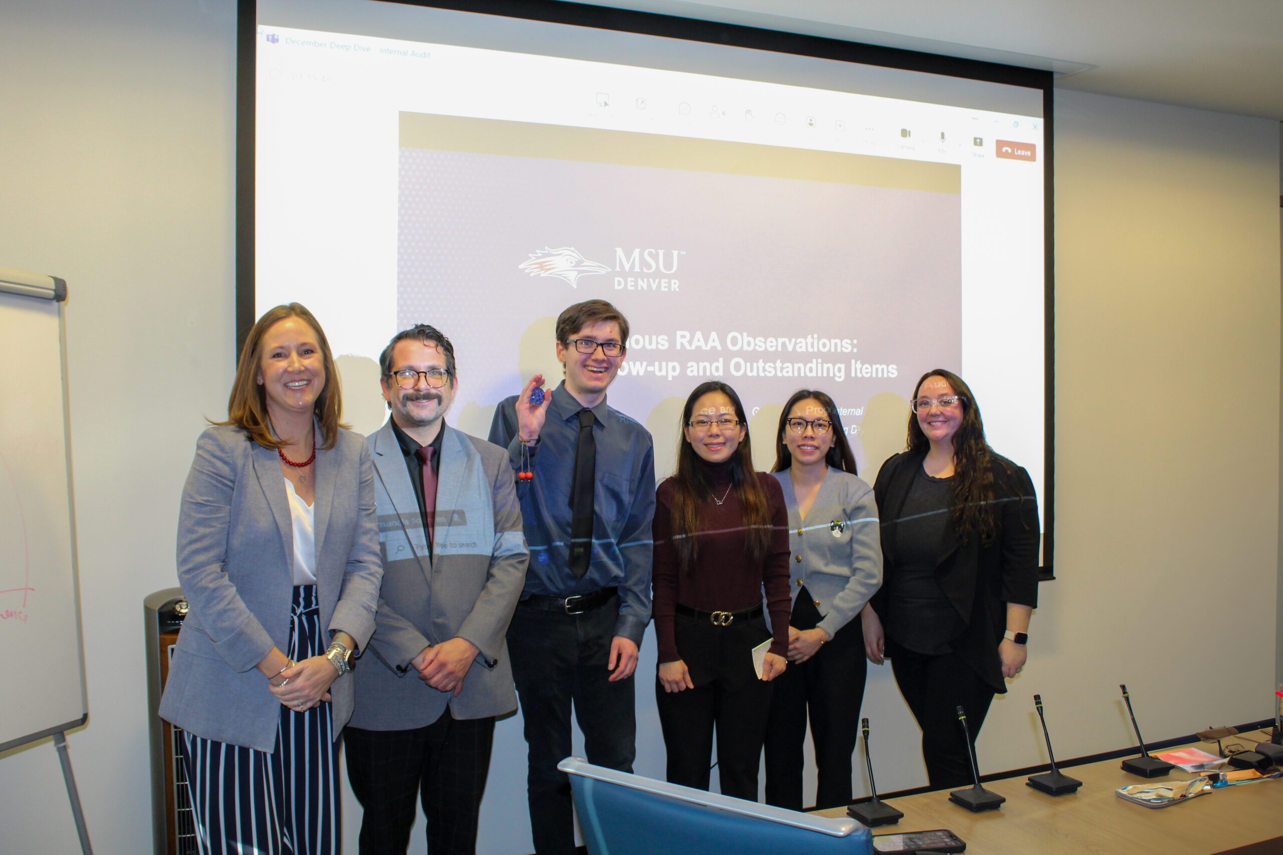 fall '24 student auditors & professor (MPAcc) smiling in front of last slide after presenting findings to senior leaders