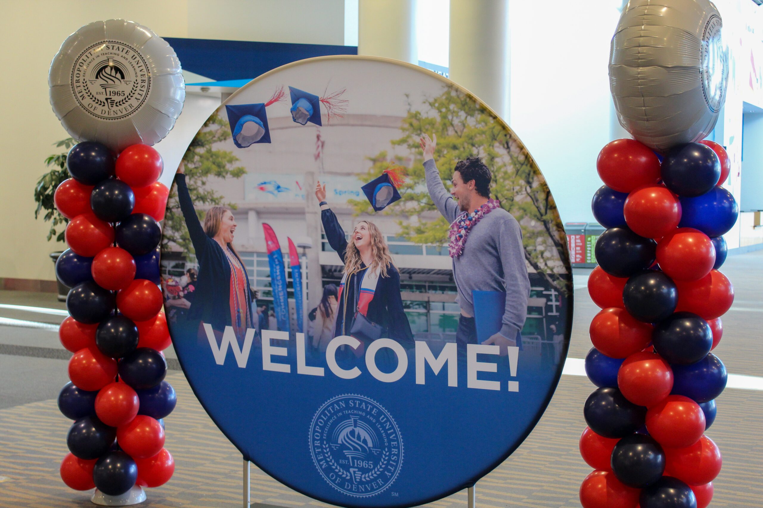 welcome sign at fall '24 commencement with 2 mini red and blue balloon towers