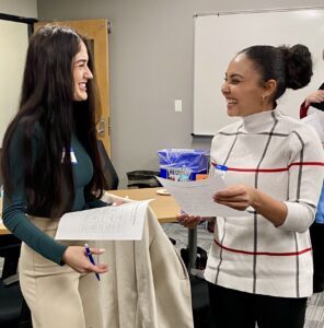 2 MPAcc students laughing while filling out networking bingo sheet - Jennifer and Francisca 