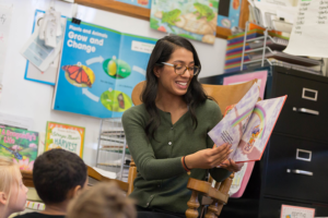 Photograph of Idalee Nunez reading a book to a group of young children in a classroom.
