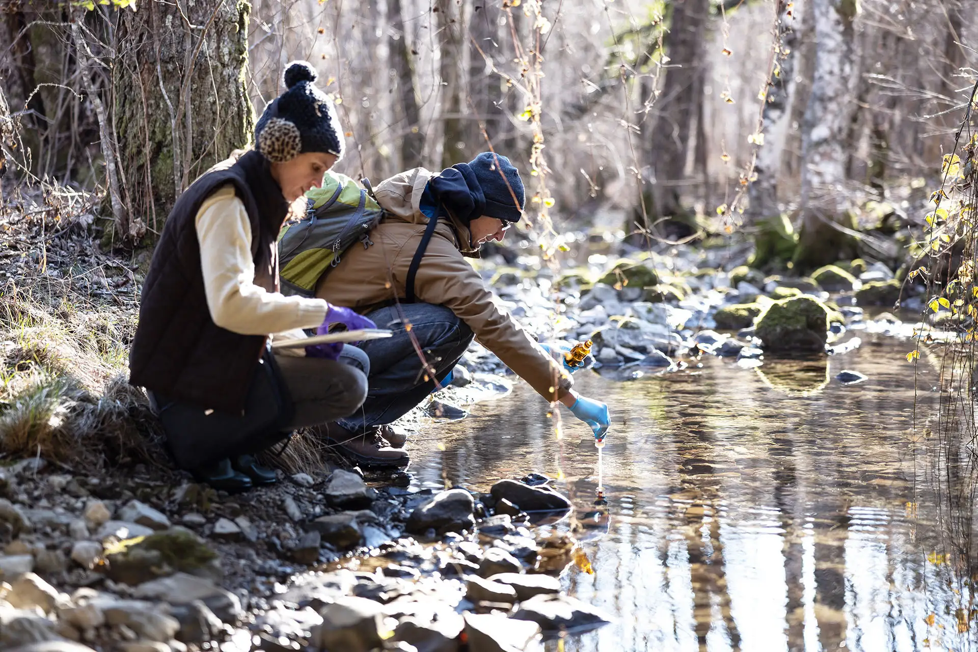 environmental engineering stock photo of two individuals by the river taking a water sample.