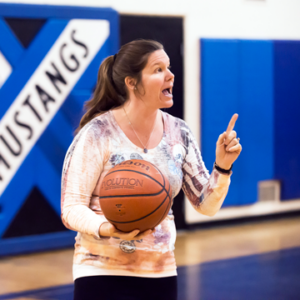 Photograph of Elizabeth Miner, Physical Education teacher, holding a basketball and talking.