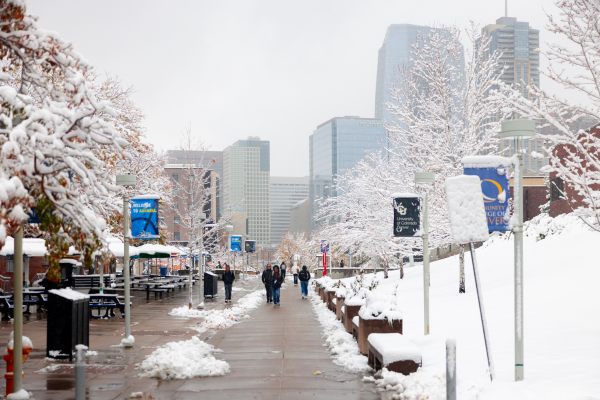 msu denver with snow on the ground and students walking with the denver skyline in background