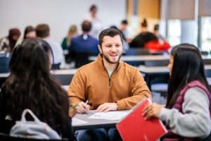 three students conversing at desk