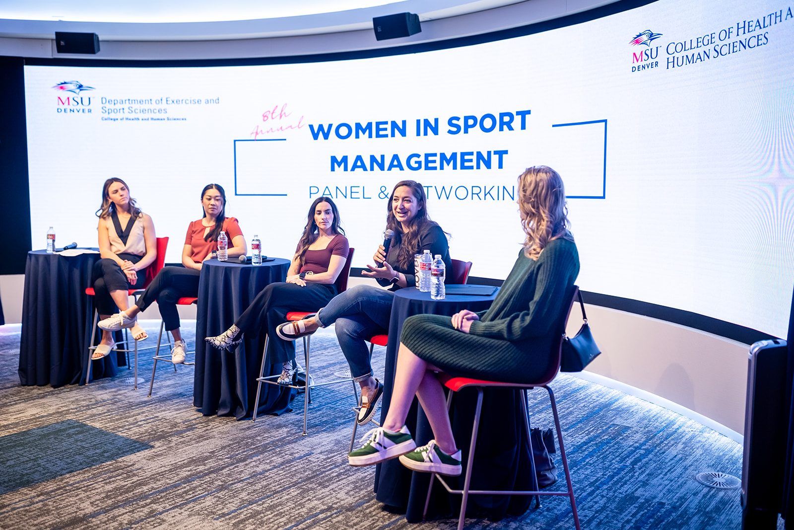 Women in Sport Management conference panel at the front of the CAVEA theater. The 8th Annual Women in Sport Management Conference took place March 11, 2025 in the JSSB CAVEA Theater. Panelists (L-R): Alyssa Svalberg, Gold Crown Foundation; Jasmine Tong, Sports Business Journal; Natalie Fresher, Kroenke Sports and Entertainment; Kelly Cavalier, League One Volleyball; and Kate Bailey, The IRONMAN Group.