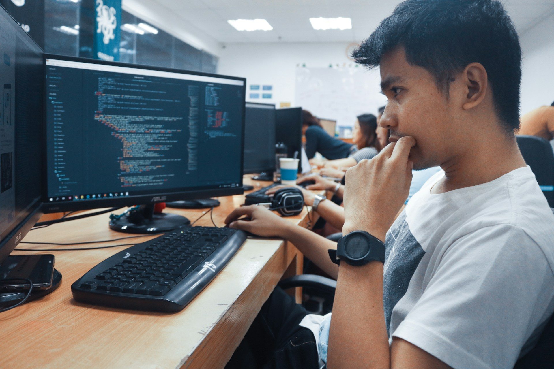 A student in a classroom reviewing work on a computer monitor.
