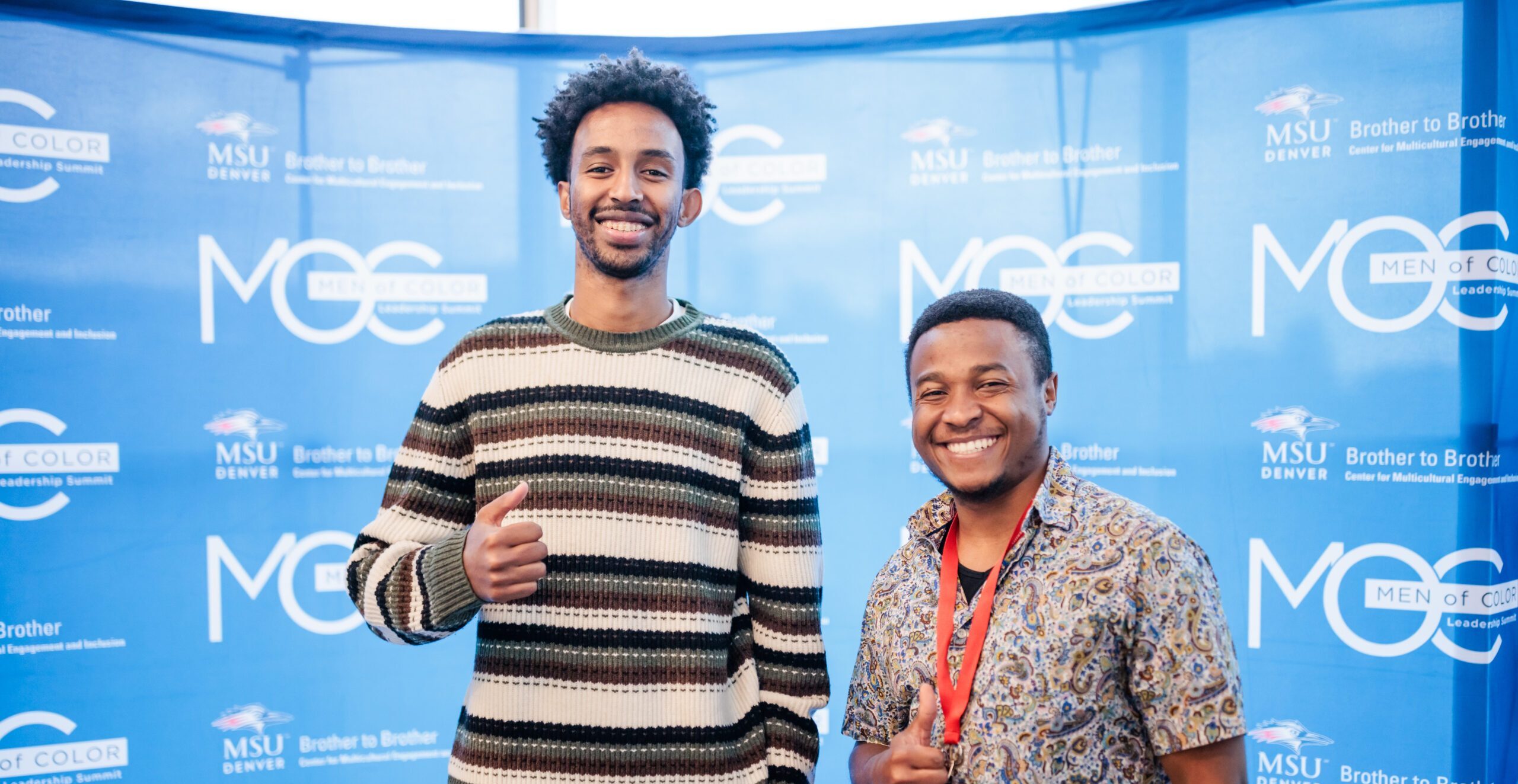 two students pose with thumbs up.
