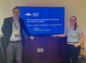 MPAcc faculty & MPAcc alum presenting at the SBI conference (Apr 2025) - Andrew and Laura standing in front of their blue MSU Denver slide