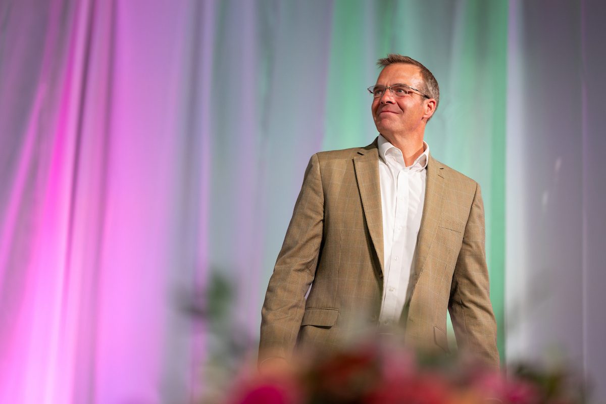 Robert Preuhs on stage in front of white background with colorful lights