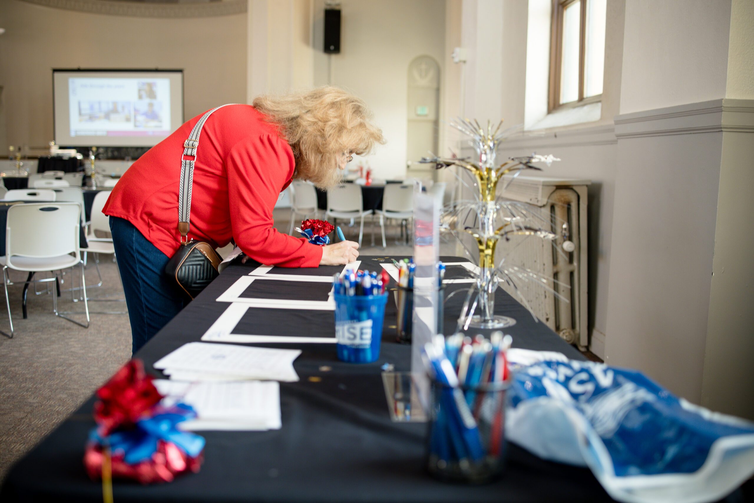 attendee at MPAcc's 15 year anniversary event signing a photo frame mat on a decorated table