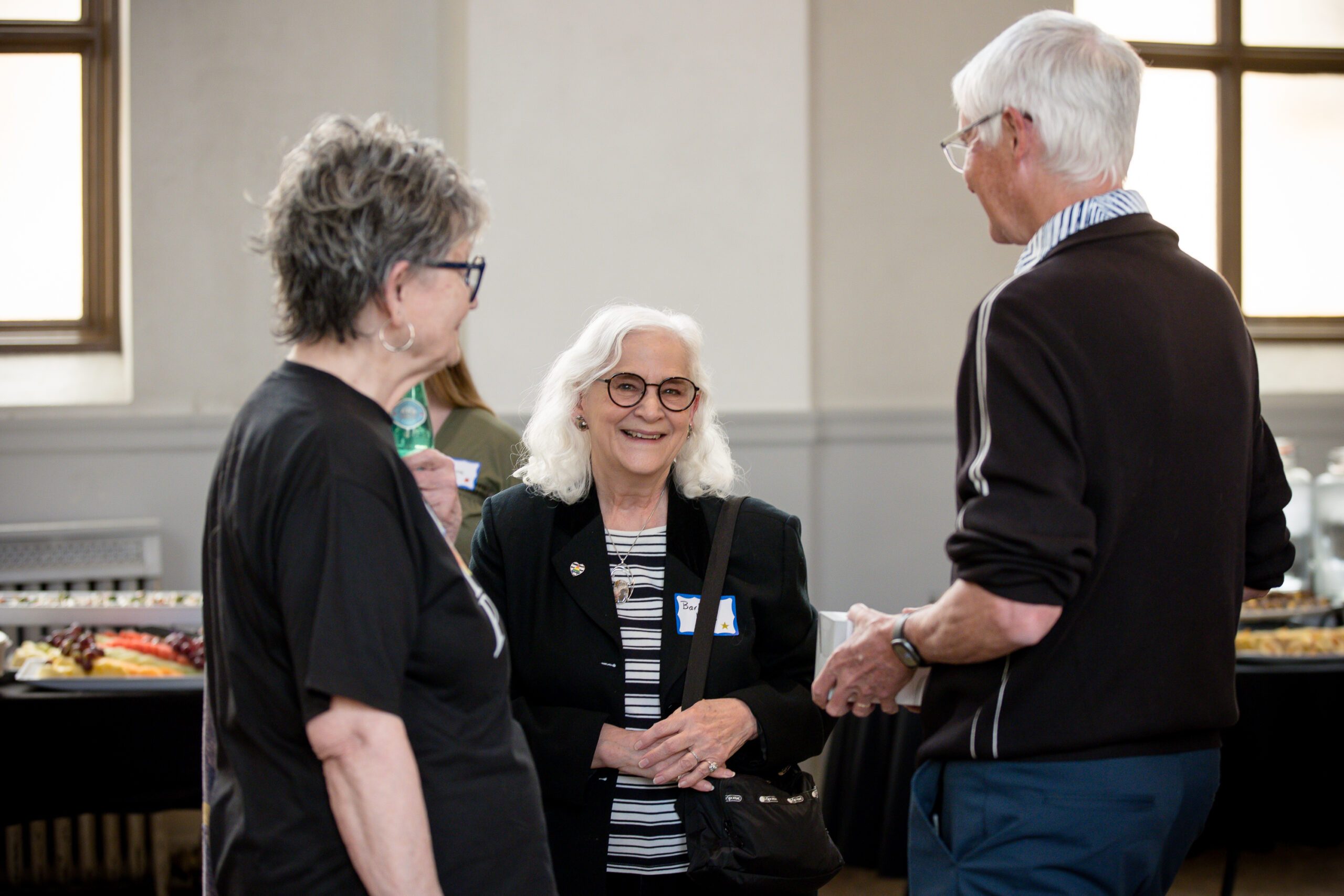 candid photo of 3 attendees talking at the beginning of MPAcc's 15 year anniversary event