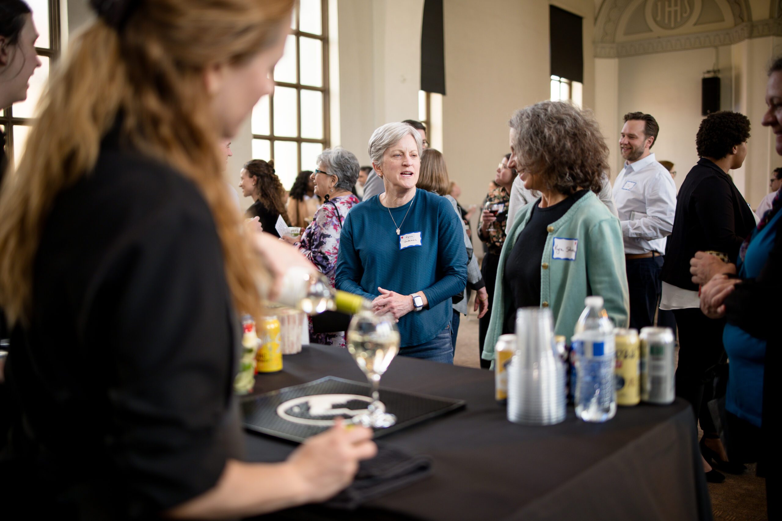 large group of alumni and faculty socializing in front of the bartender at MPAcc's 15 year anniversary event