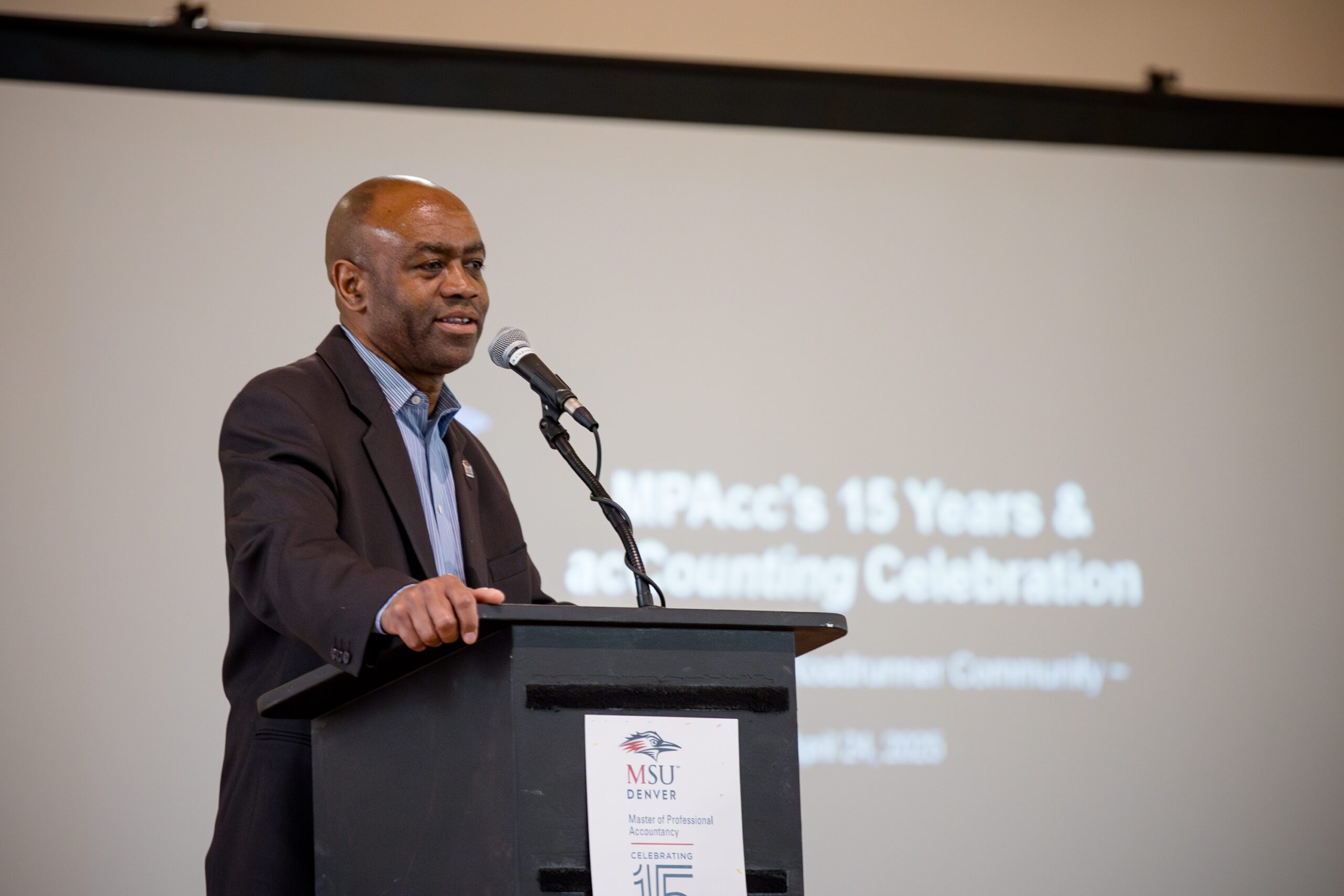 MPAcc's 15 year anniversary - Director talking at the podium in front of intro slide