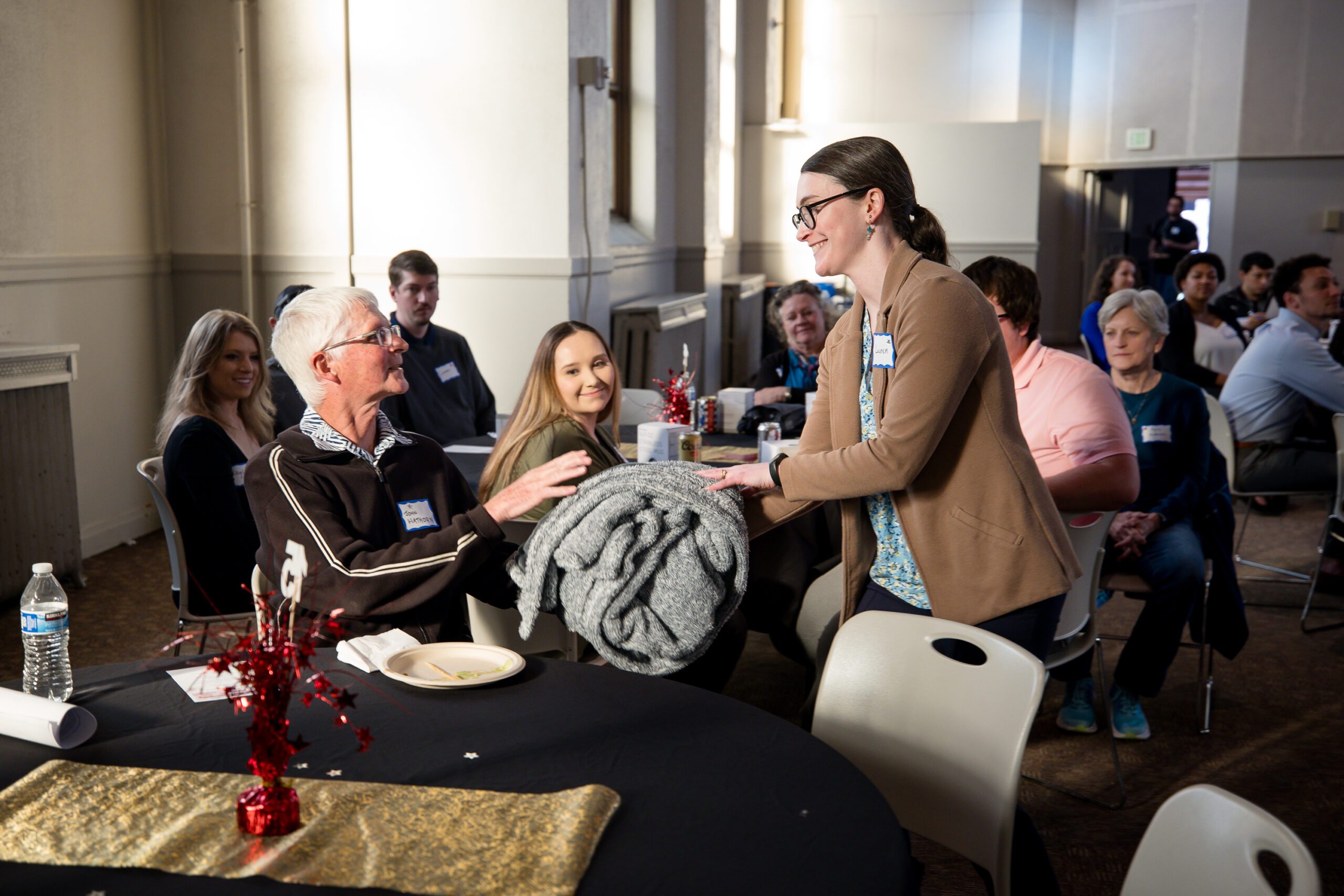 MPAcc's 15 year anniversary event - staff member handing a gift to one of the emeritus faculty as attendees clap