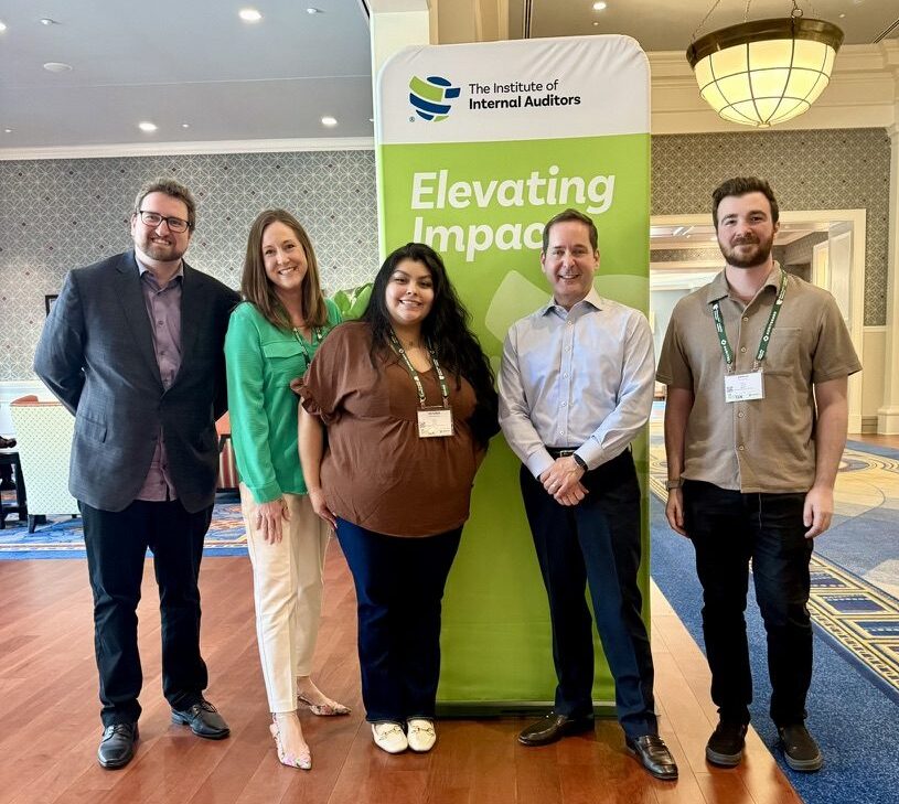 3 students and faculty standing in front of IIA sign meeting CEO at Spring 20205 IIA conference