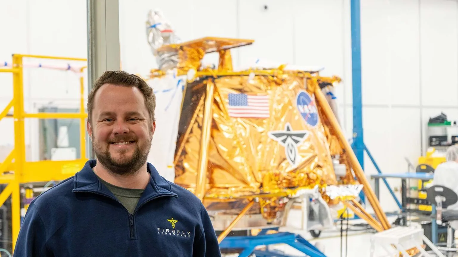 Alumnus Tyler Gilchrist stands by a lunar lander.
