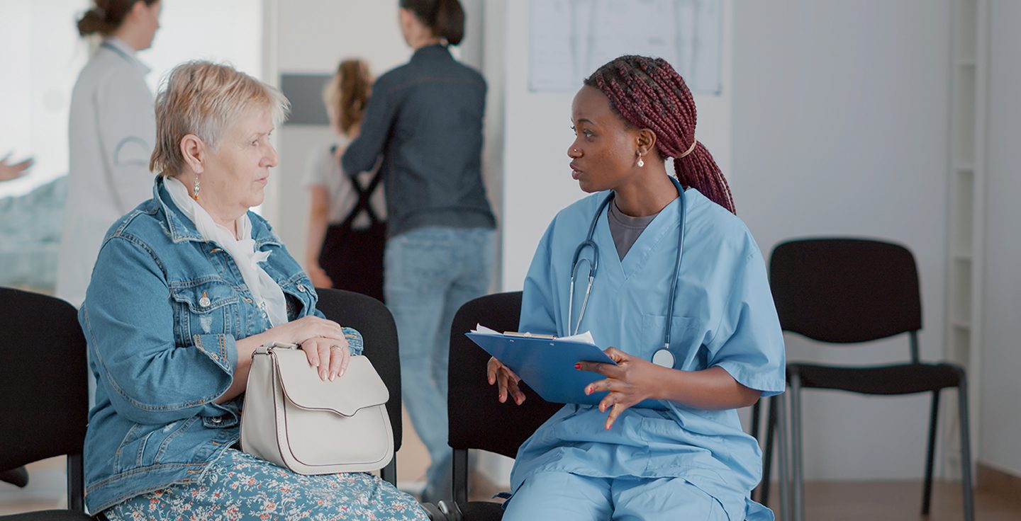 African american nurse talking to elder woman in waiting room