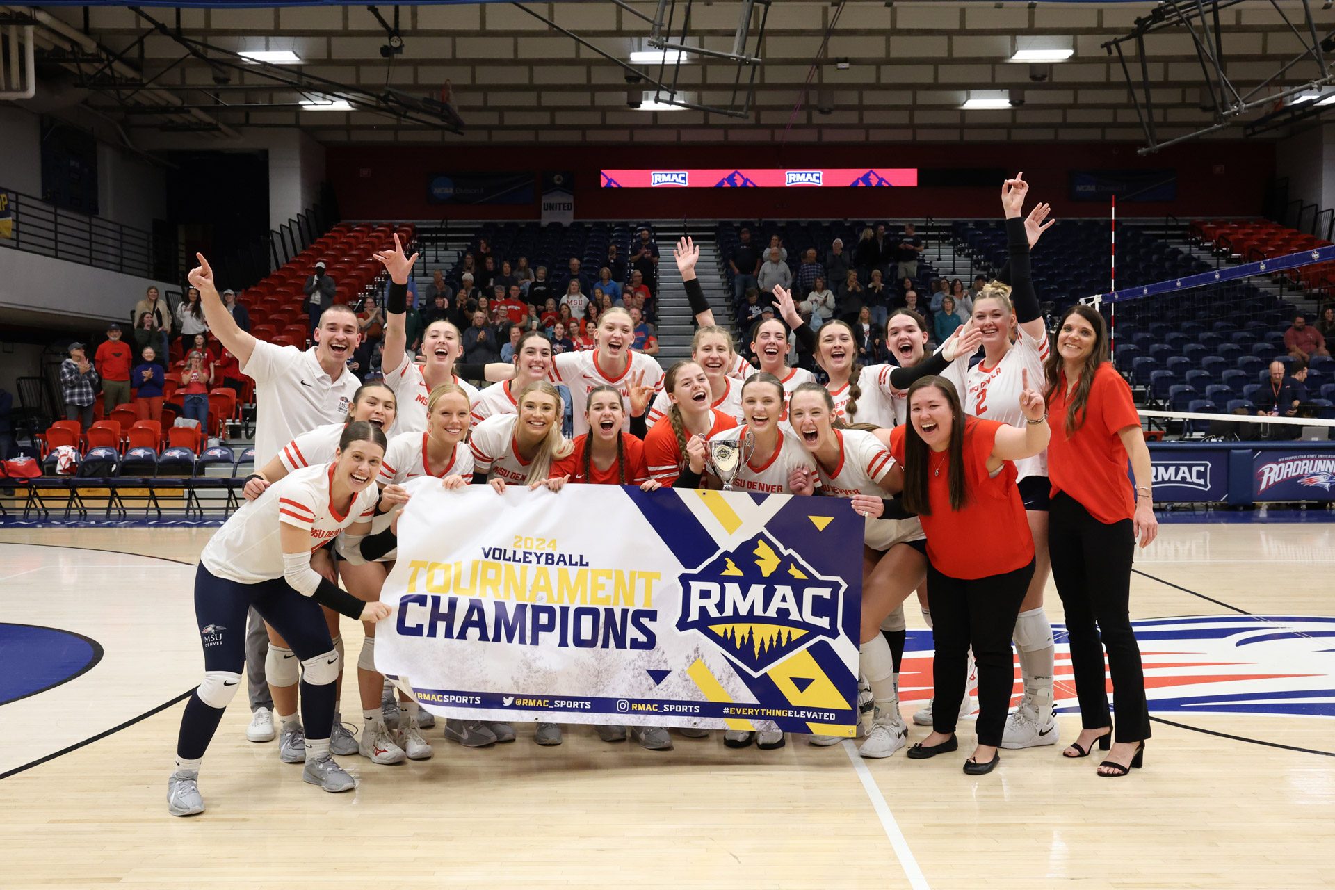 MSU Denver's volleyball team celebrates with the RMAC Championship banner after the 2024 conference championship