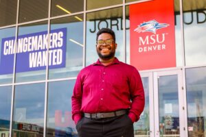2025 MSU Denver graduate Chrisnel Akele standing in front of JSSB on campus